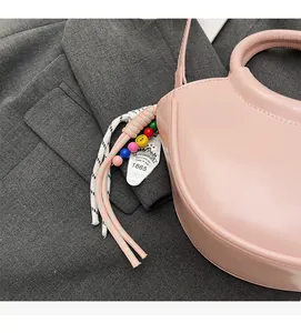 Detailed close-up of pink leather bucket bag with colorful beads and decorative cords
