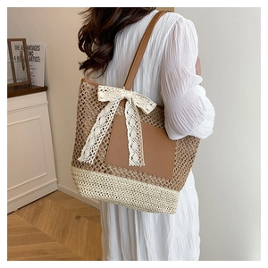Vue détaillée du sac cabas en paille tissée avec couleurs contrastées et nœud en dentelle