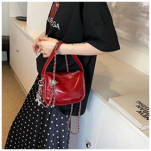 Close-up of glossy red patent leather handbag with silver chain and fashion logo