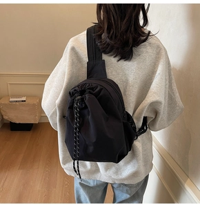 Détail d'un sac bandoulière en nylon noir avec une poche à cordon coulissant pratique