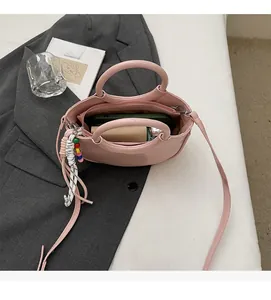 Spacious interior of a pink half-moon bucket bag with phone and beaded pendant detail