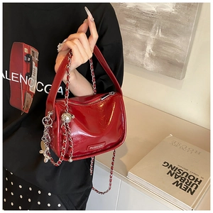 Detail of red patent leather handbag featuring gold metal chain and FASHION logo