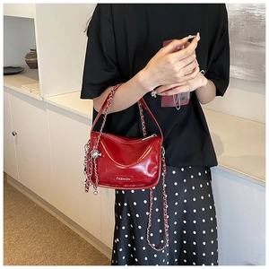 Detail of red patent leather handbag with silver chain strap and metal charm