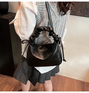 Detail of the soft black leather scrunchie handle and drawstring design of the cloud bag