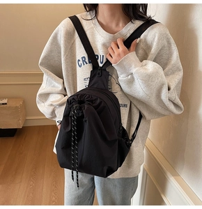 Détail de la sangle réglable et du zip latéral sur un sac à dos multifonction en nylon noir