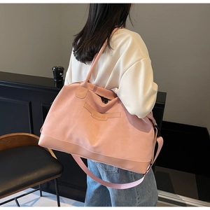 Grand sac de voyage rose porté par un mannequin montrant taille et texture