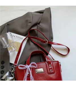Detail of red glossy leather bucket bag with mesh bow and heart-shaped pendant
