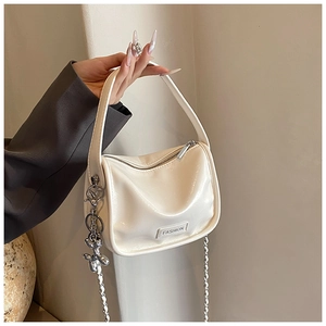 Detail of off-white patent leather handbag with silver chain and cute balloon dog charm