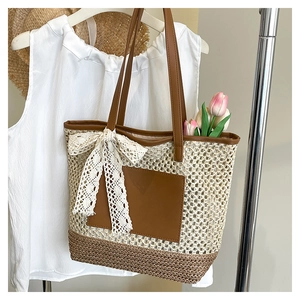 Détail du sac cabas en paille tressée avec accents en cuir brun et nœud en dentelle