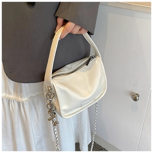 Detail of cream glossy handbag with silver chain and decorative metal balloon dog charm