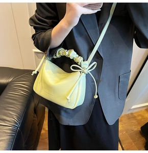 Detail of light green PU leather crossbody bag with pleated handle and bow knot detail