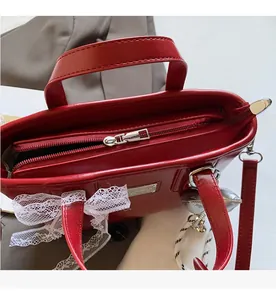 Detail of red leather bucket bag with white lace trim and smooth silver zipper closure