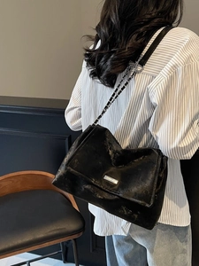 Retro black textured tote bag with silver chain strap shown worn by a model in a side view
