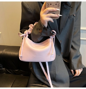 Detail of pink croissant bag with pleated handle and embossed fashion text decoration