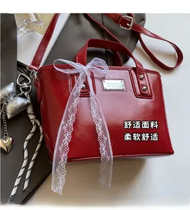 Detail of red oil wax leather bucket bag with white lace bow and silver heart charms