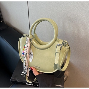 Detail of sage green handbag featuring colorful beaded strap and outdoor style pendant