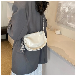 Detail of elegant beige crossbody bag with silver chain and cute balloon dog charm
