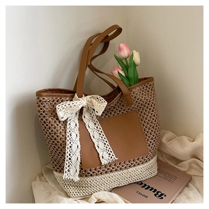 Détail macro du sac cabas en paille bicolore avec bordure en similicuir et nœud en dentelle