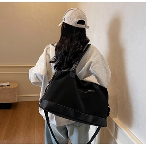 Vue détaillée du grand sac cabas noir avec poignées en cuir et bandoulière réglable