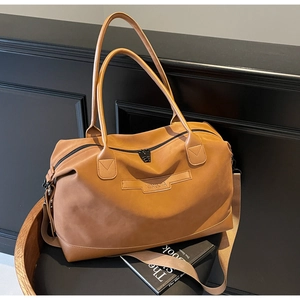 Détail d'un grand sac de voyage marron avec écusson en cuir et fermetures éclair robustes
