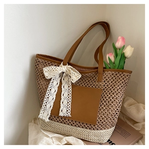 Détail du sac cabas en paille tressée avec couleurs contrastées et nœud en dentelle