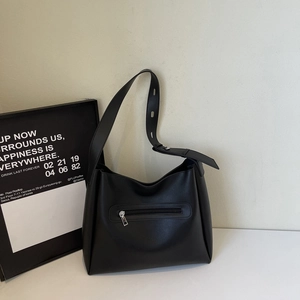Detail view of large black bucket bag showing front zipper pocket and adjustable strap