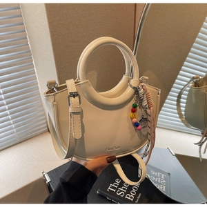 Detail of cream bucket bag showing smooth PU leather texture and colorful beaded charm