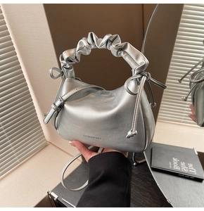 Detail of silver metallic dumpling bag featuring pleated handles and side drawstring ties