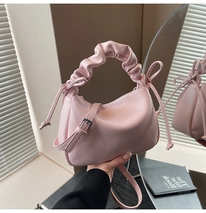 Detail view of pink leather half-moon bag with gathered handle and drawstring side accents