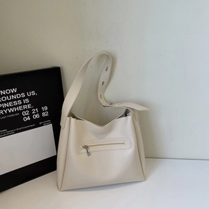 Detail of beige bucket bag with front zipper pocket and adjustable wide shoulder strap