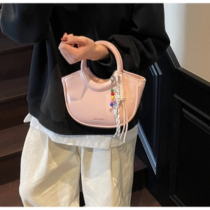Detail of pink glossy crescent bag with round handle and colorful beaded charm