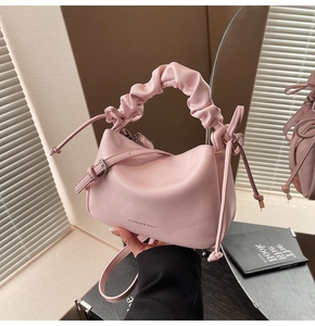 Detailed shot of pink leather dumpling bag with ruched handle and side string details