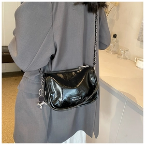 Detail of black glossy handbag featuring silver chain and cute balloon dog charm