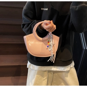 Detail of light pink patent leather bucket bag with beads and brand logo tag