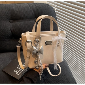 Macro detail of beige faux leather bucket bag with silver bow and lace ribbon accessory