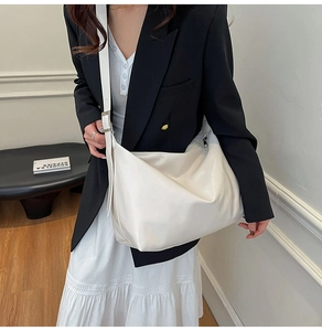 Close-up of cream crescent crossbody tote bag with soft faux leather texture for work