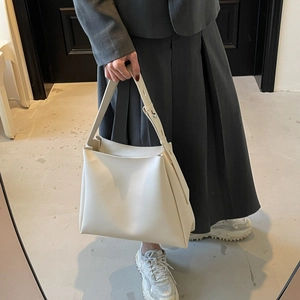 Detail of off-white minimalist bucket bag with adjustable wide strap and silver buckle