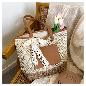 Détail du sac cabas en paille avec poche en cuir marron et nœud en dentelle sur une chaise
