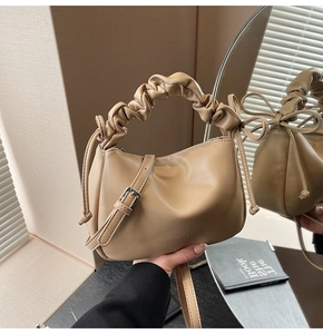 Detailed view of beige dumpling bag featuring pleated cloud handle and bow drawstring knots