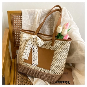 Détail d'un sac cabas tissé beige avec nœud en dentelle et anses en cuir marron sur chaise