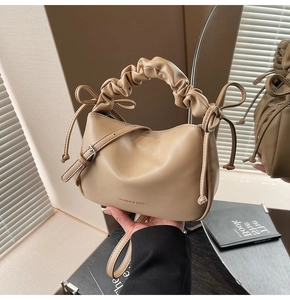 Detail of a beige dumpling bag with ribbon ties and a soft ruched handle