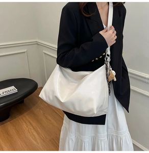 Minimalist glossy white tote bag shown with stars keychain and stylish black suit