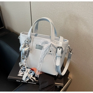 Detail of light blue crossbody bucket bag with lace bow and silver heart pendant