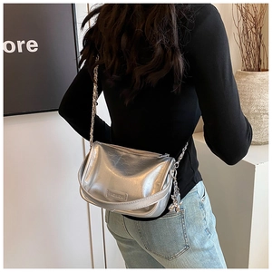 Detail of silver metallic crossbody bag featuring FASHION metal plate and chain strap