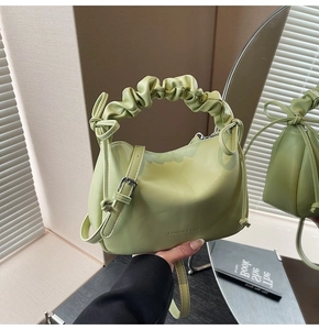 Detail of avocado green pleated pillow bag showing drawstring and metal buckle closure