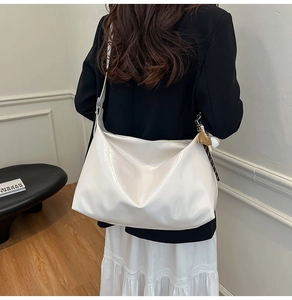 Detailed view of white glossy tote bag with cute bear pendant on a shoulder strap