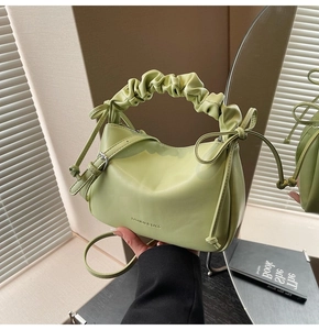 Close-up of soft avocado green faux leather handbag with ruffled cloud-style handle details