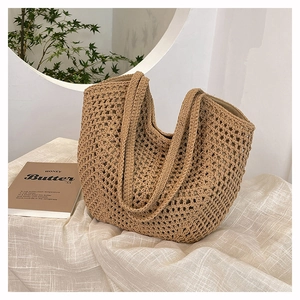 Detail of hollow crochet texture and woven handle on this khaki straw tote bag