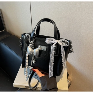 Detail of black leather bucket bag with silver hardware and lace bow decoration