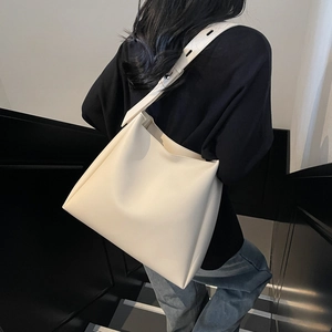 Minimalist beige PU leather bucket bag shown on shoulder with adjustable strap detail